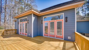 A modern house with a wooden deck, large glass doors, and a clear view of the surrounding trees. - Spacious Hampton Vacation Home Near Beaches! (Hampton)