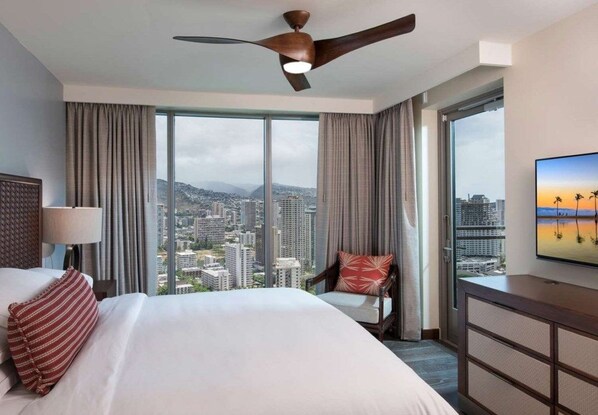 Habitación de hotel con una cama grande, una silla, un televisor y vistas a la ciudad.