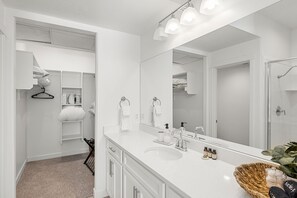 Features a walk-in shower with a glass door and a spacious vanity with a curved sink and mirror.