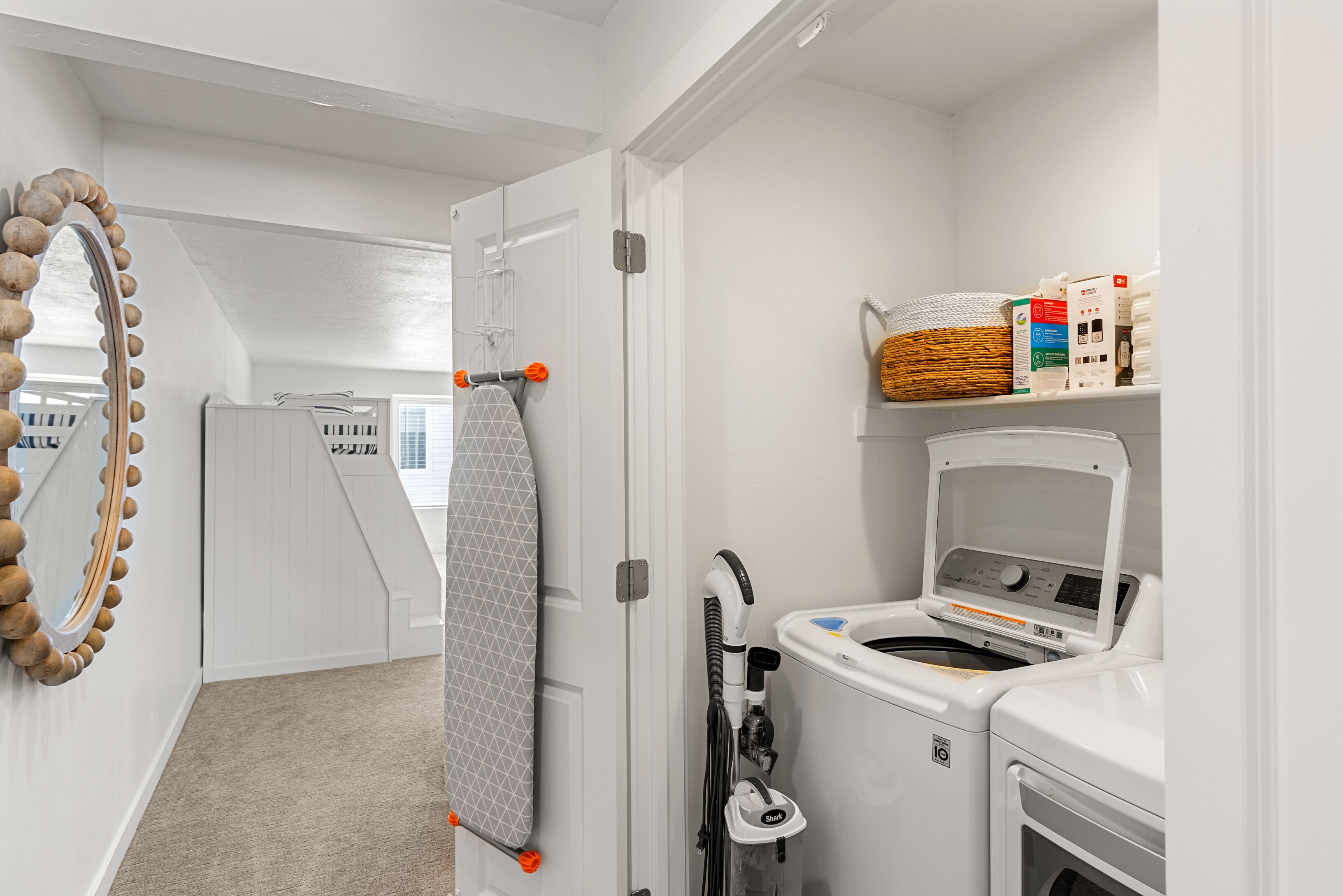 Un espace buanderie équipé d’un lave-linge, d’un sèche-linge et d’une planche à repasser.