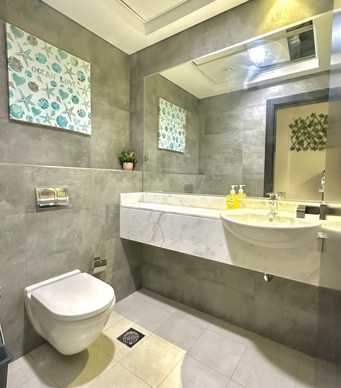 A bathroom with a toilet, sink, and a mirror.