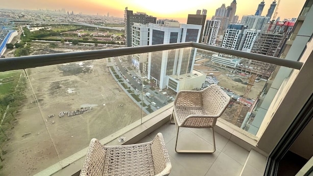 A balcony with wicker chairs and a city view at sunset. - Lakeside Hostel Downtown (Dubai)
