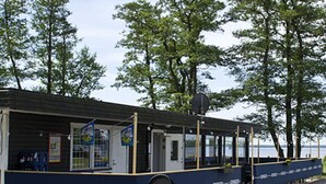 Ein Restaurant am Wasserufer mit Terrassenplätzen, einem überdachten Bereich und Blick auf das Wasser.