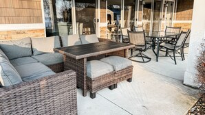 A covered patio area with wicker furniture, a table, and chairs.