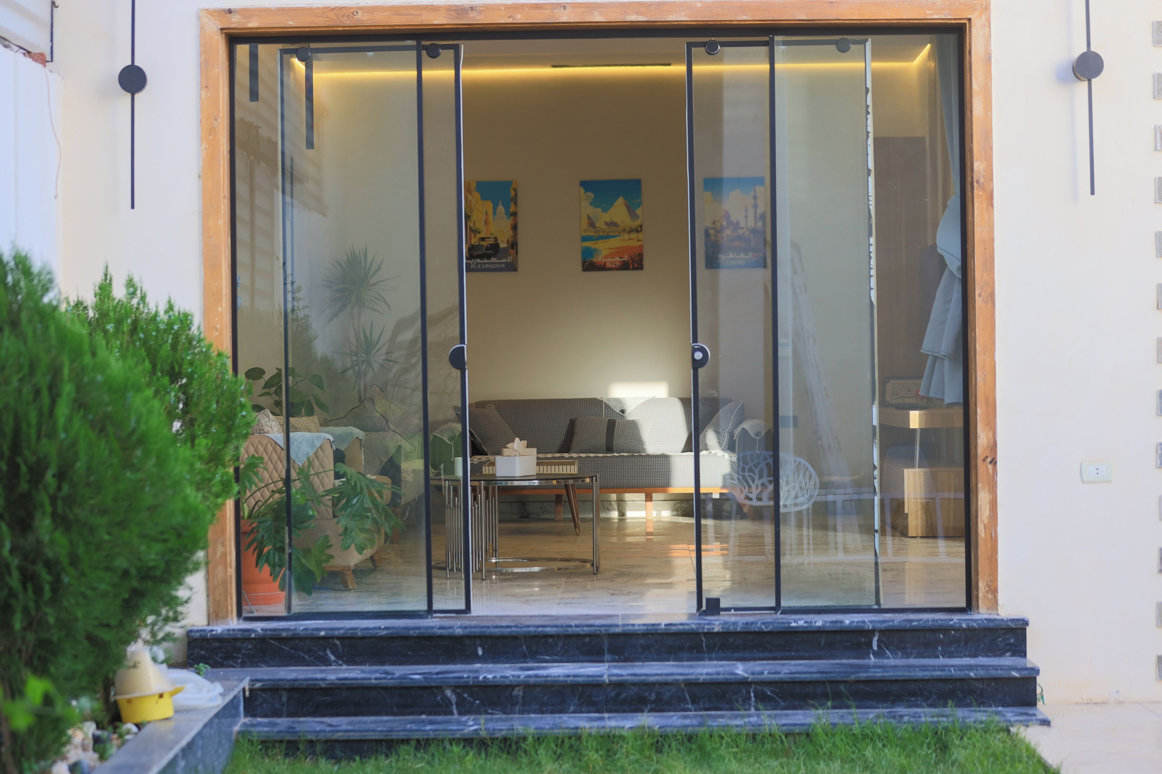 A modern entrance with a glass door, a sofa, and a table inside.