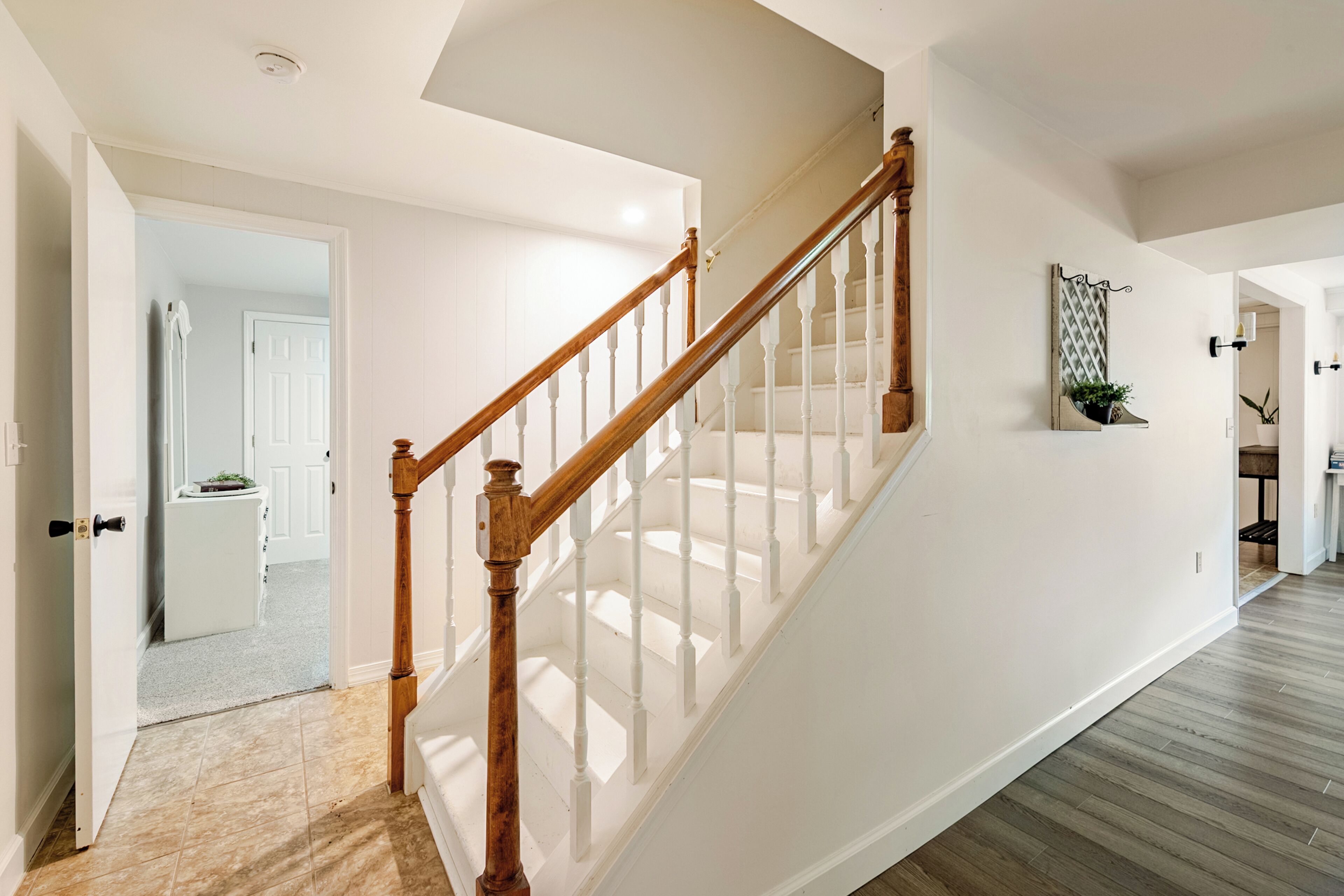 A staircase with wooden balusters and a white handrail leading to an upper floor.