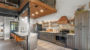 Une cuisine moderne dotée d’un îlot central, de tabourets de bar et d’un mur d’accent en pierre.