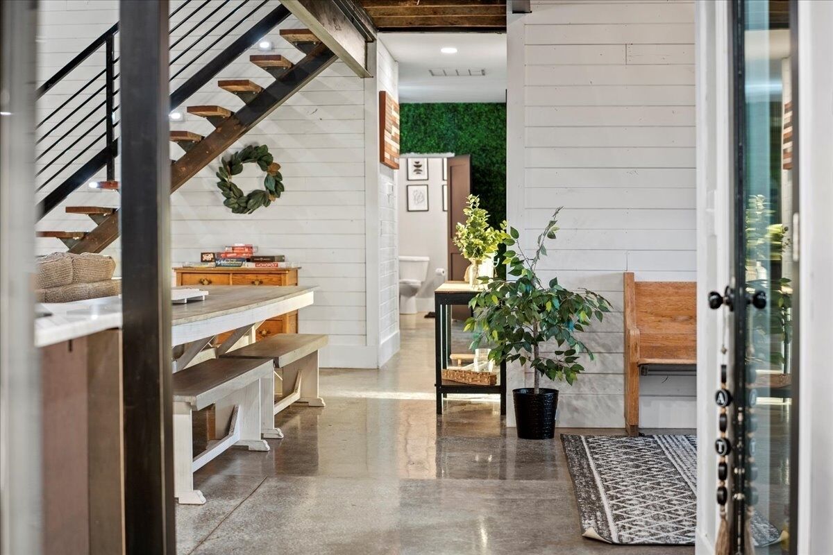 A modern interior with a staircase, a dining area, and a living space with a green wall and a potted plant.