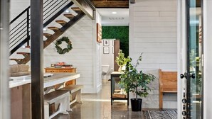Un intérieur moderne comprenant un escalier, un coin repas et un espace de vie agrémenté d’un mur végétal et d’une plante en pot.