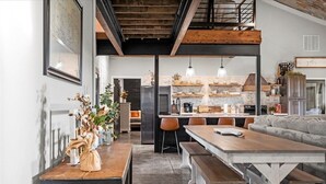 Une cuisine moderne avec un mur en briques, des poutres en bois et un coin repas comprenant une table et des bancs en bois.
