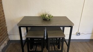A dark wooden table with two matching chairs and a small plant on top.