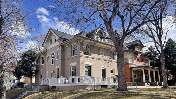 A two-story house with a front porch, a driveway, and a well-maintained lawn.