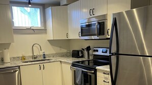 A modern kitchen with stainless steel appliances, white cabinets, and a wooden floor.