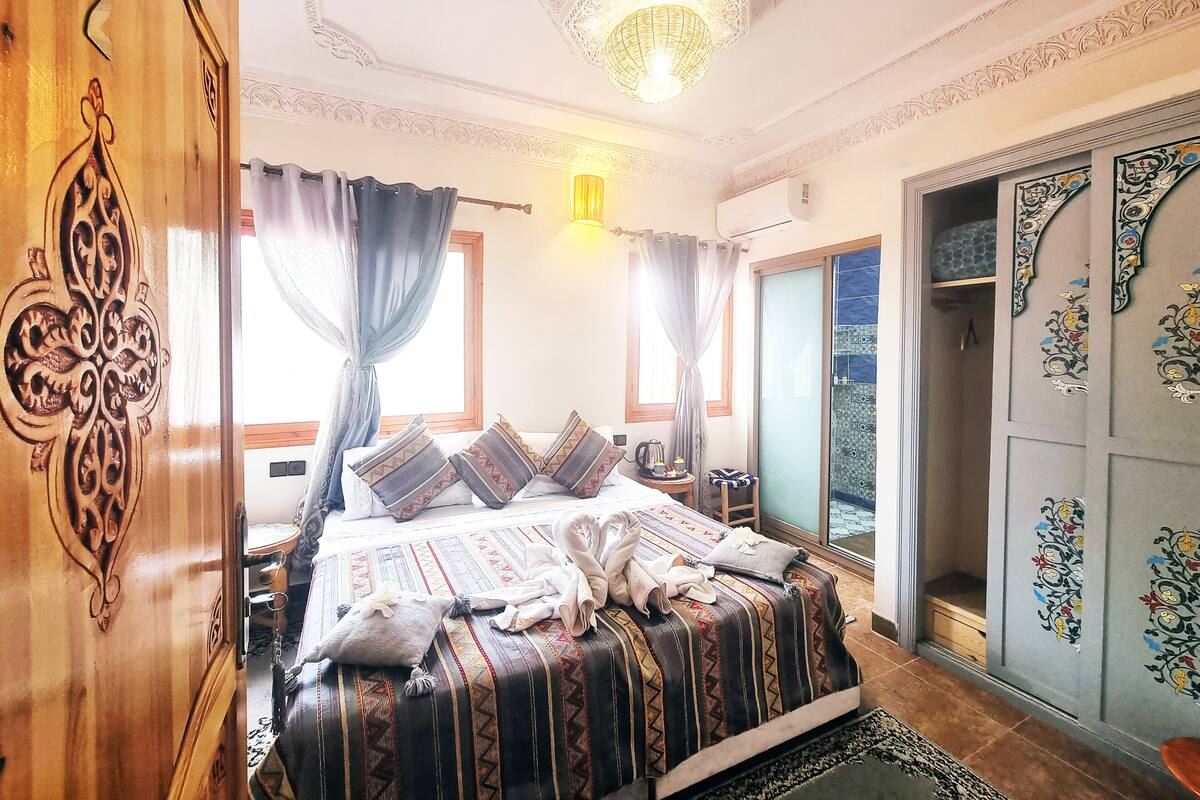 Un dormitorio con cama, cortinas, una araña y un armario con paneles decorativos.