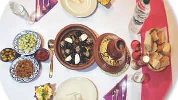 Una mesa dispuesta con diferentes platos, incluyendo un tazón de aceitunas, una rebanada de pan y una botella de agua.