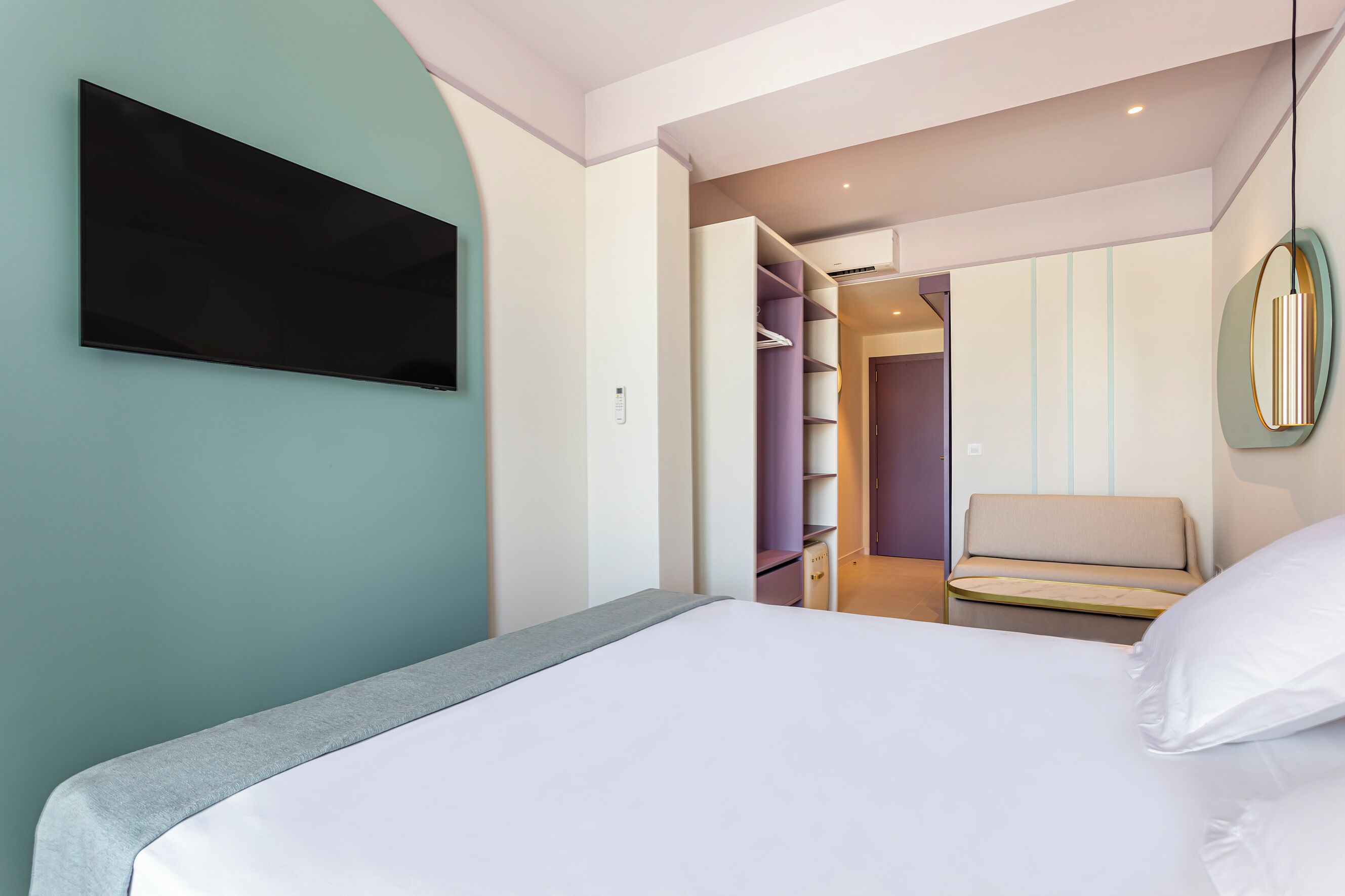 A modern bedroom with a bed, a TV mounted on the wall, and a walk-in closet with shelves.