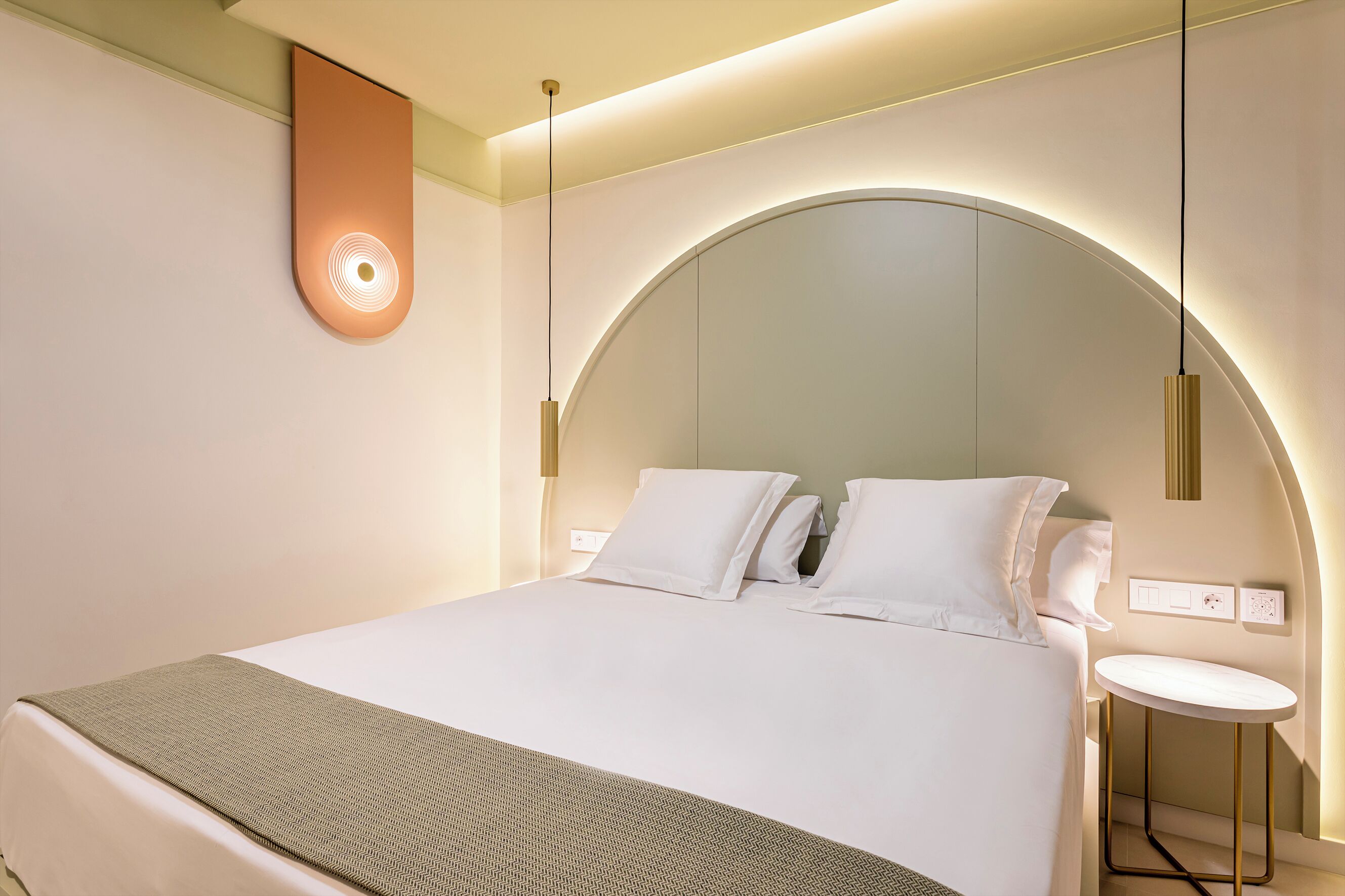 Ein modernes Hotelzimmer mit einem großen Bett, einem Nachttisch und einem einzigartigen, gewölbten Deckenstil.