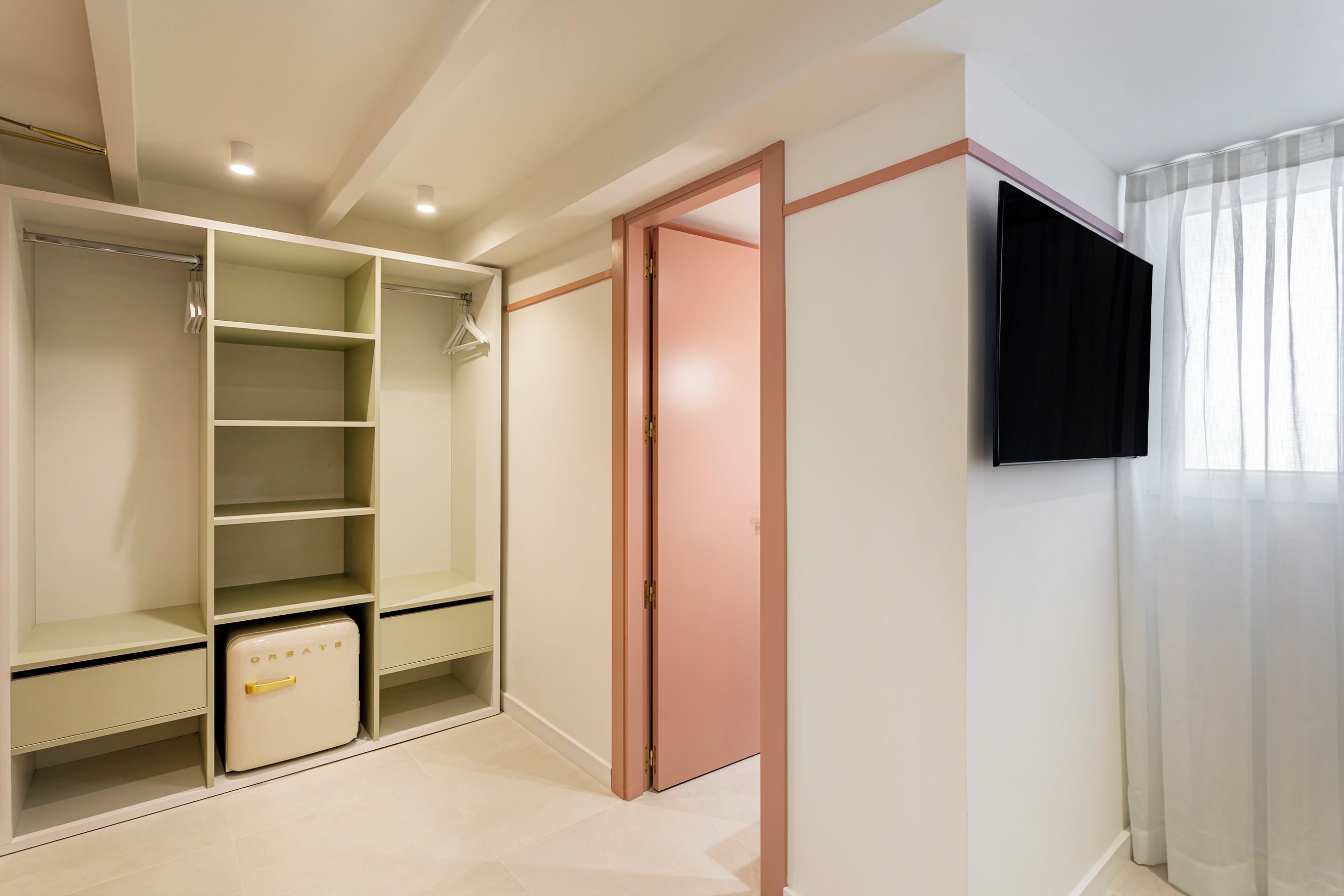 A walk-in closet with open shelves, a small refrigerator, and a pink door.