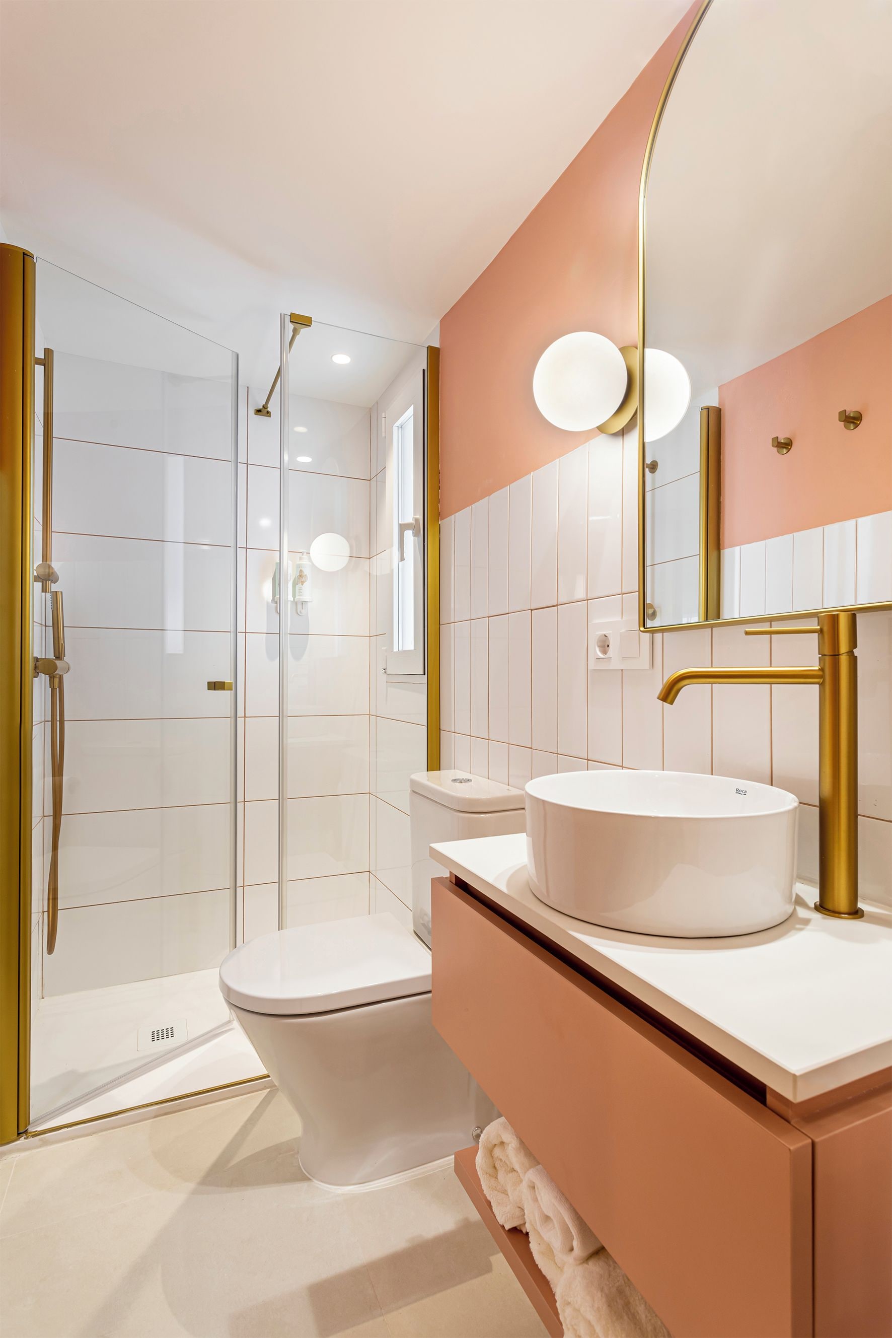 A modern bathroom with a glass-enclosed shower, a white toilet, a round sink, and a vanity with a mirror.