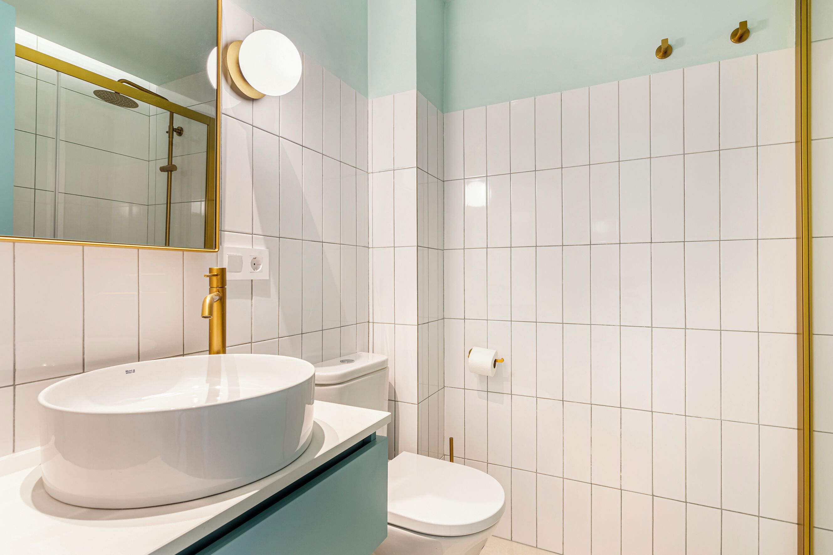 Ein modernes Badezimmer mit Waschbecken, Toilette und Spiegel, alles in Weiß.