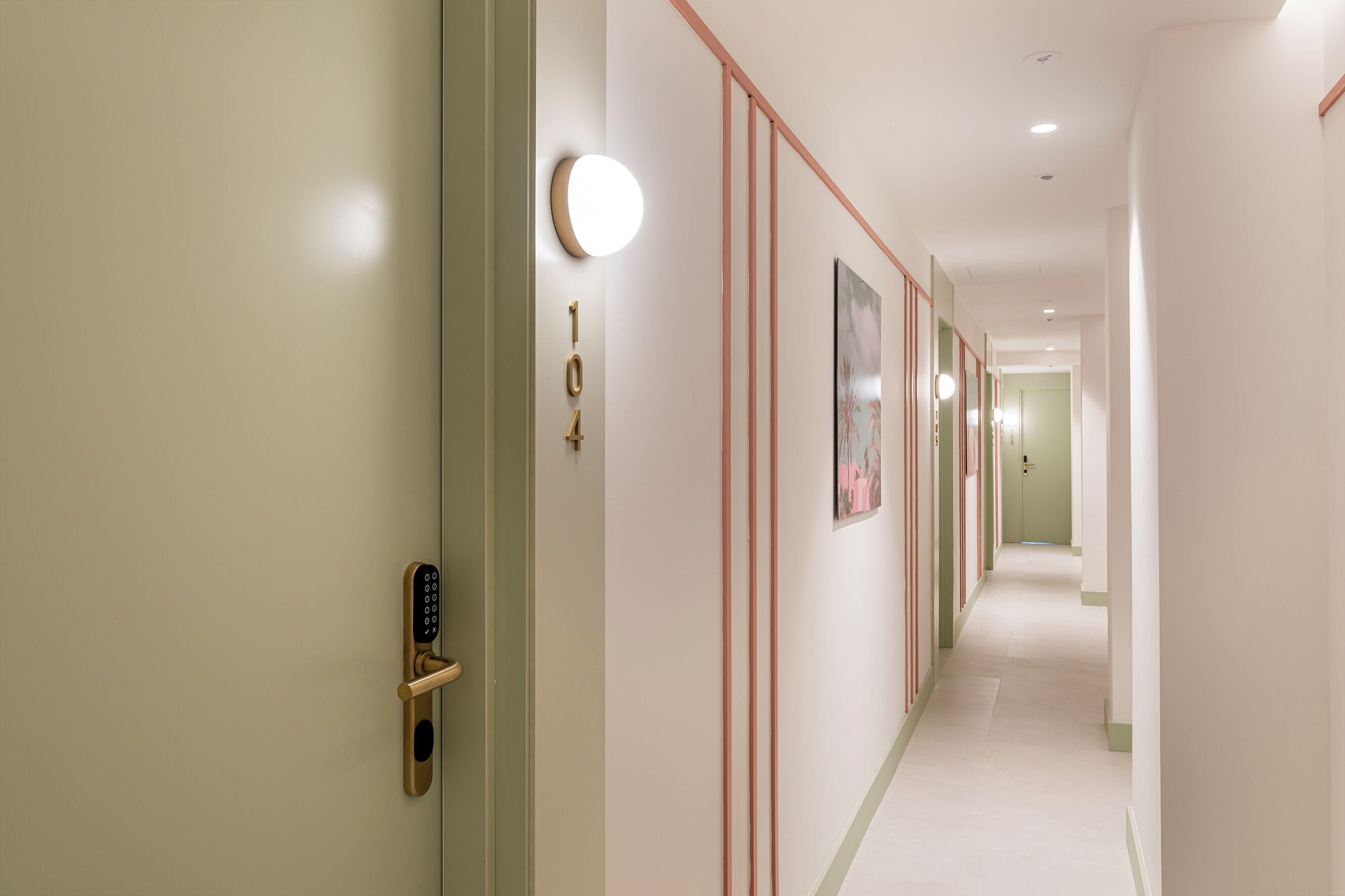 A hallway with a modern door, a wall-mounted light, and a door number.
