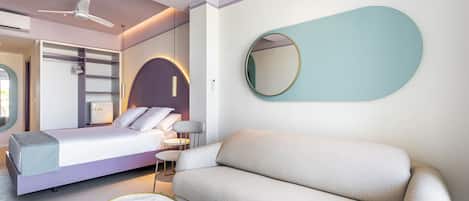 A modern bedroom with a bed, a sofa, a round mirror, and a ceiling fan.