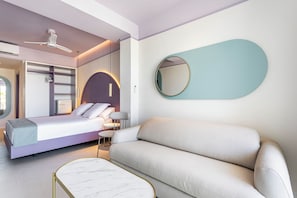 A modern bedroom with a bed, a sofa, a round mirror, and a ceiling fan.