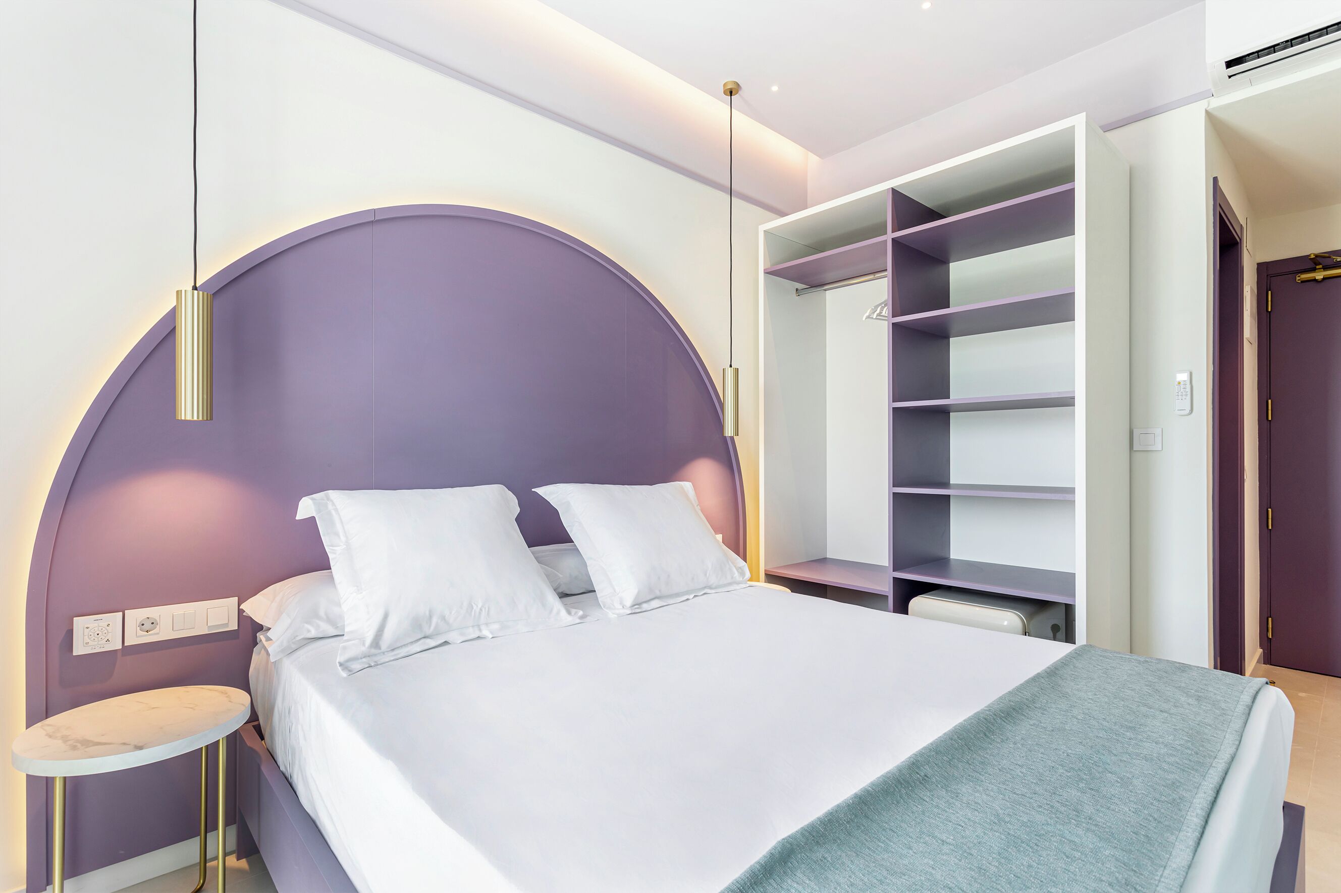A modern bedroom with a bed, bedside table, and built-in shelving.