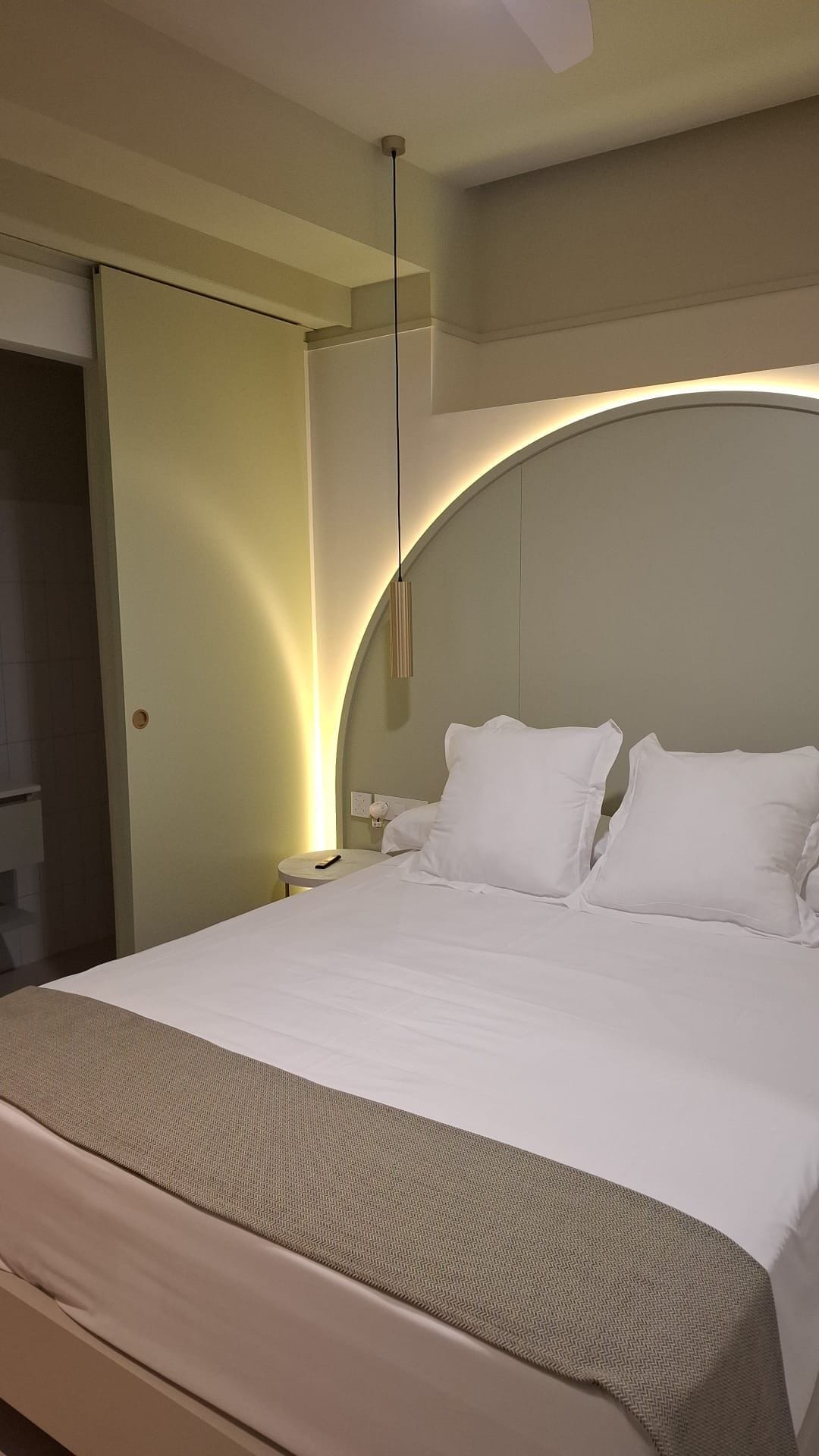 Une chambre d’hôtel avec un grand lit, une table de chevet et une armoire.