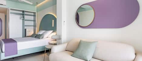 A modern bedroom with a bed, a sofa, a round mirror, and a ceiling fan.