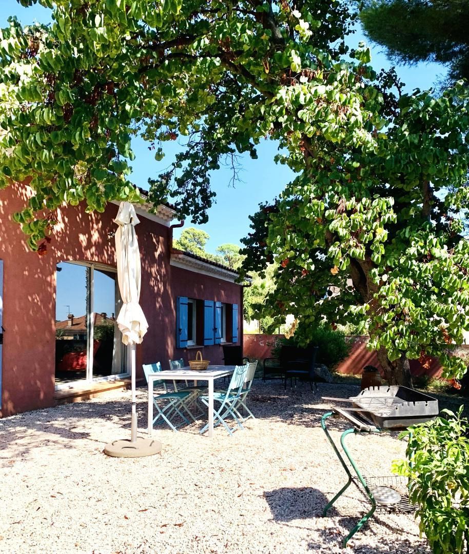 A patio area with a table and chairs, a hanging white cloth, and a grill.