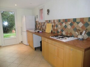 Una cocina con estufa a gas, refrigerador, armarios de madera y salpicadero con diseño.