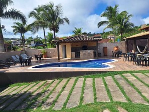 Un patio trasero con piscina, muebles de patio y zona de barbacoa.