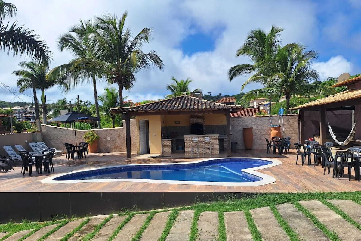 Une piscine avec une terrasse carrelée, un espace salon extérieur et un coin barbecue.