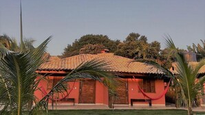Um edifício com fachada vermelha e telhas de barro, rodeado por palmeiras.