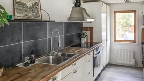 A kitchen with dark tiled backsplash, stainless steel sink, wooden countertop, and white cabinets. - Lovely home in Norrtälje with sauna (Norrtälje)