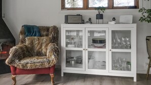 A room with a fur-covered armchair, a white cabinet with glass doors, and a window above. - Lovely home in Norrtälje with sauna (Norrtälje)