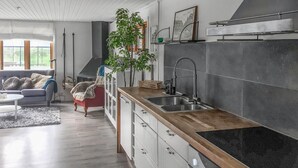 A modern kitchen with a wooden countertop, a built-in sink, and a large window. - Lovely home in Norrtälje with sauna (Norrtälje)