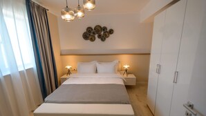 A modern bedroom with a large bed, bedside lamps, a decorative wall piece, and a wardrobe. - Gioia Sea View (Navodari)
