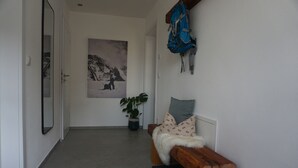 A hallway with a wooden bench, a potted plant, a wall-mounted backpack, and a framed picture on the wall. - 4-star Ott vacation apartment - with separate garden - at the foot of the Buchenberg (Halblech)