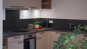 A modern kitchen with a black countertop, white cabinets, and a built-in oven. - 4-star Ott vacation apartment - with separate garden - at the foot of the Buchenberg (Halblech)