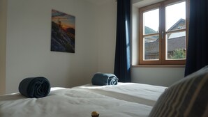 A room with two beds, a window with curtains, and a painting on the wall. - 4-star Ott vacation apartment - with separate garden - at the foot of the Buchenberg (Halblech)
