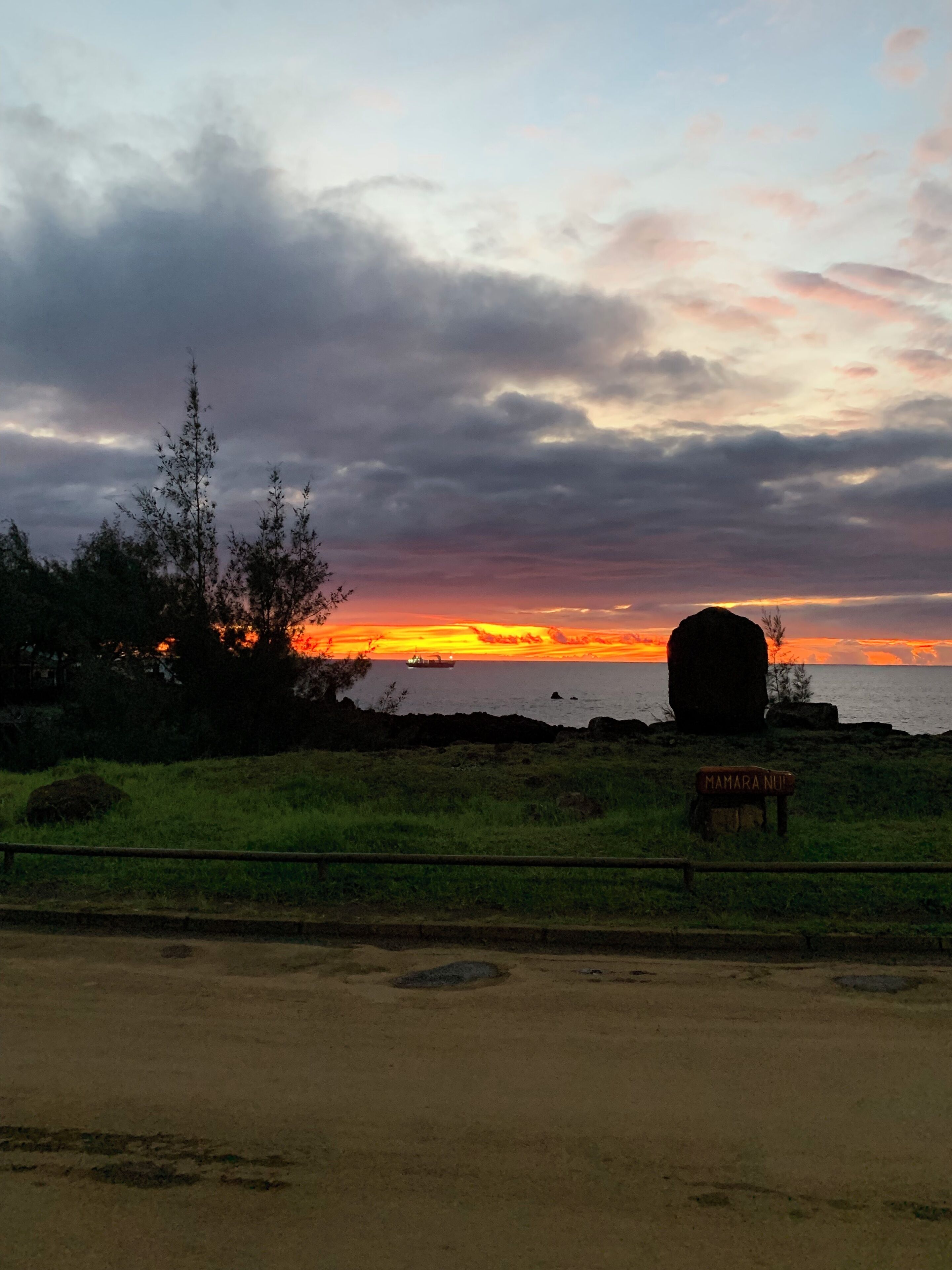 A sunset view with a large rock formation and a sign reading "MAMARA NUI".