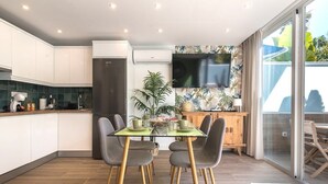 Una cocina moderna con gabinetes blancos, horno empotrado y un televisor de pantalla plana montado en la pared.