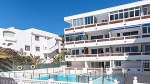Un hotel de varios pisos con piscina, escaleras exteriores y una terraza con baldosas.