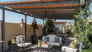 An outdoor patio with a covered seating area, a sofa, and potted plants.