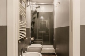 A compact bathroom with a toilet, sink, and glass-enclosed shower.