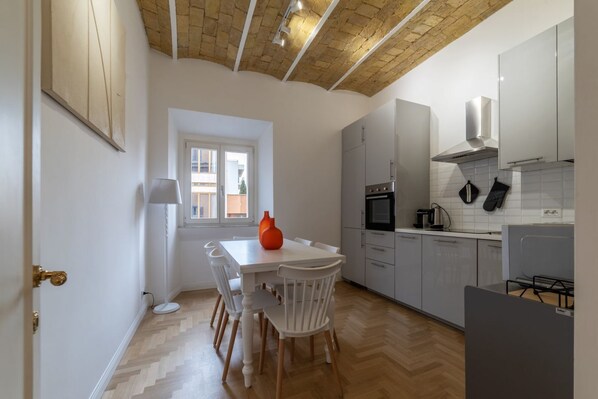 A modern kitchen with white cabinets, a wooden herringbone floor, and a window with a view.