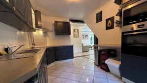 A modern kitchen with dark cabinets, stainless steel appliances, and a tiled floor.