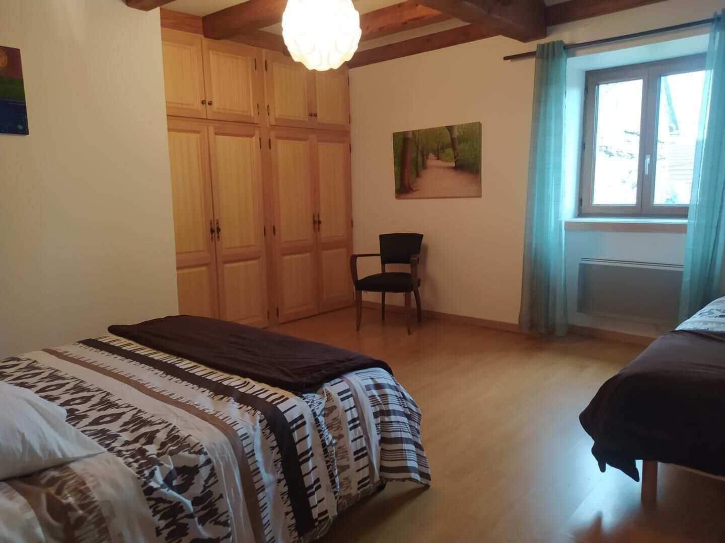 A bedroom with a bed, a chair, a wardrobe, and a painting on the wall.